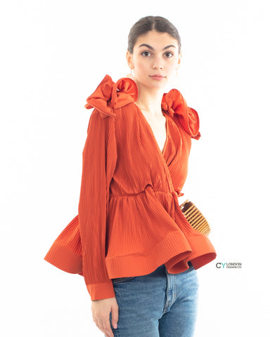 Pleated shirt with ruffle hem and floral design on shoulder in orange